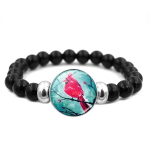Detailed macro view of black beaded bracelet featuring a red cardinal bird glass cabochon