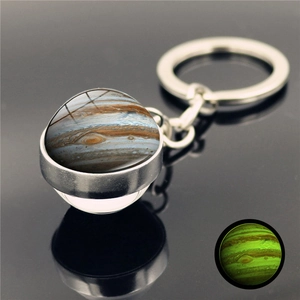 Detail of Jupiter sphere keychain with glow-in-the-dark effect on reflective black surface