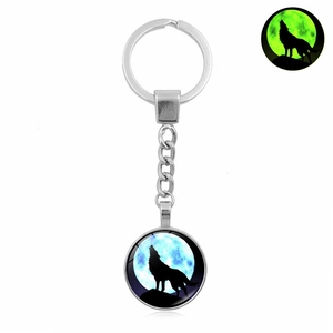Luminous howling wolf glass keychain showing green glowing effect in the dark