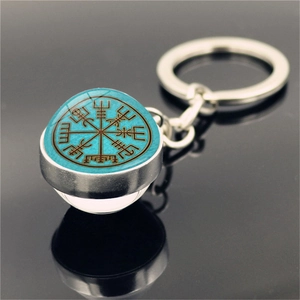 Close-up of Viking Vegvisir compass pendant keychain on black reflective surface
