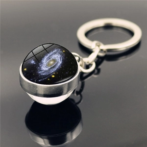 Détail du porte-clés galaxie avec sphère en verre et nébuleuse spirale sur surface miroir sombre