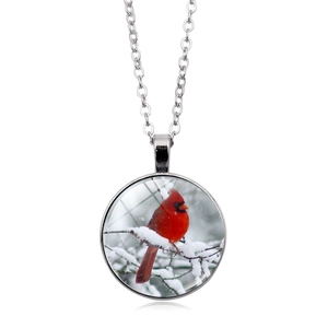 Macro view of silver glass pendant necklace featuring a red cardinal bird on snow branch