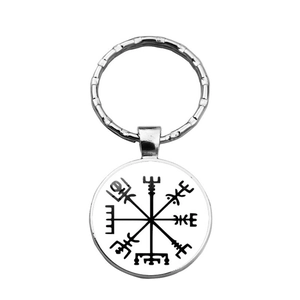 Close-up of silver metal Viking compass Vegvisir keychain on plain white background