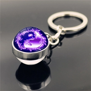 Macro shot of Yin Yang keychain with purple flame pattern under glass dome on black surface