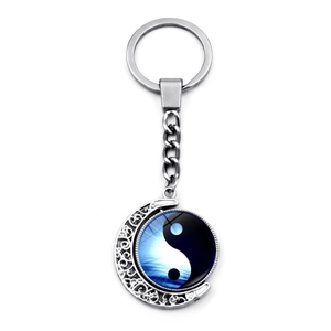 Macro shot of silver crescent moon keychain with rotating yin yang pendant and blue gradient