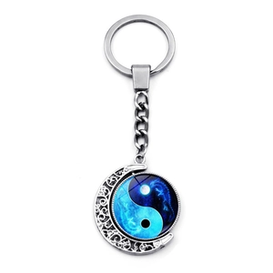 Close-up of rotating yin-yang pendant on silver moon frame keychain with starry details
