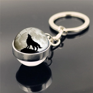Porte-clés loup hurlant avec dôme en verre et anneau argenté sur fond noir réfléchissant