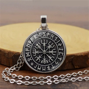 Close-up of vintage Viking compass pendant with runic engraving on a wooden surface