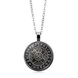 Close-up of vintage Viking compass pendant with runes and Celtic knot on white background