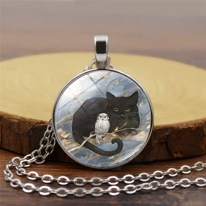Détail macro du pendentif argenté avec illustration chat noir et petite chouette
