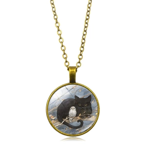 Détail du pendentif vintage en bronze avec chouette et chat noir sous cabochon en verre