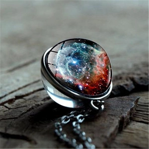 Vue macro d'un collier pendentif boule de verre nébuleuse sur fond en bois vintage