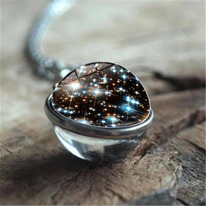 Collier pendentif galaxie nébuleuse avec sphère en verre sur fond en bois sombre