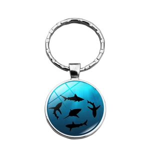 Détail d'un porte-clés en métal argenté avec motif de requins dans l'océan bleu profond