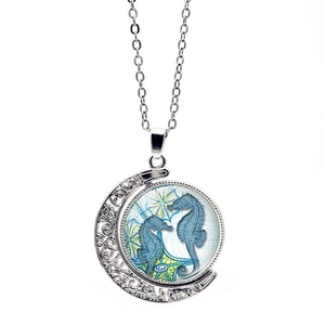 Detalle del colgante de luna creciente giratoria con caballitos de mar azules y plata