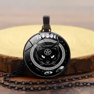 Close-up of gothic black cat pendant with pentagram and moon phases on wood