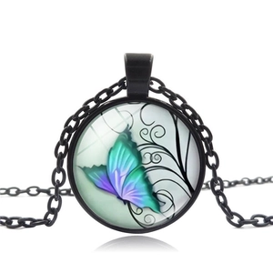 Detail of a vintage black butterfly pendant necklace with a glass dome and colorful artwork