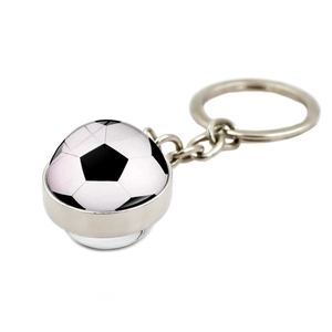 Gros plan d'un porte-clés foot en verre avec anneau métallique sur fond blanc pur
