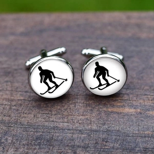 Detailed view of silver ski silhouette cufflinks on dark wood texture background