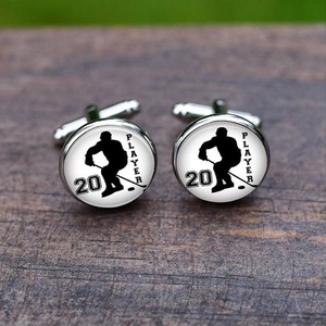 Detail of silver hockey player cufflinks with number 20 on a dark wooden surface