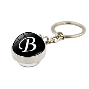 Minimalist metal keychain with glass dome pendant featuring white alphabet B design