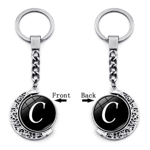 Rotating silver moon keychain with double-sided letter C pendant on grey background