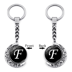 Rotating silver moon keychain detail showing both sides of the letter F pendant