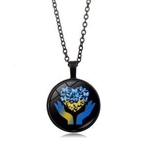 Dettaglio macro della collana con ciondolo in vetro e motivo a cuore a farfalla blu e giallo