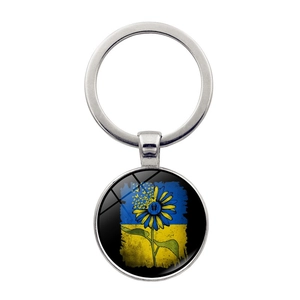 Detail of round metal keychain featuring sunflower butterfly motif in blue and yellow colors