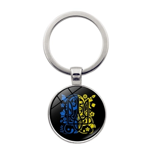Detail of round metal keychain with Ukraine trident emblem and floral glass pendant