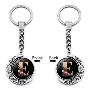 Detail view of double-sided rotating crescent moon keychain with floral letter E pendant