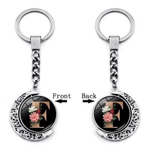 Close-up of double-sided rotating moon keychain with letter F and floral pattern