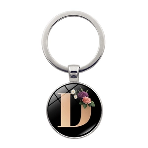 Detail of silver metal keychain with letter D and floral design under glass cabochon