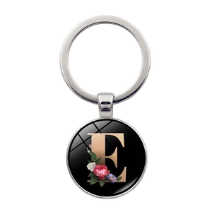 Detail of silver keychain with letter E and floral pattern on a black round pendant