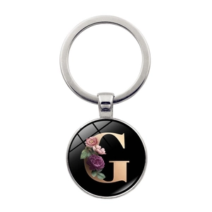 Detailed macro view of silver keychain with letter G and purple floral motif charm