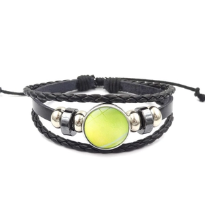 Detail van een meerlaagse leren tennisarmband met verstelbaar koord en glazen bedeltje