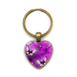 Detalle de un llavero de corazón vintage con mariposa púrpura y marco de metal de bronce