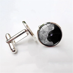 Detail of silver cufflinks showing a black cat silhouette with purple eyes under glass