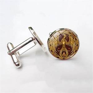 Detail of silver alloy cufflinks featuring golden phoenix on a dark red glass dome