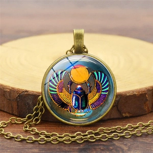 Détail d'un pendentif scarabée égyptien en bronze avec motifs soleil bleu et vert