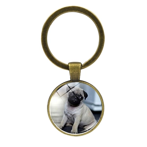 Detail of a vintage bronze puppy keychain with a round pug photo glass dome pendant