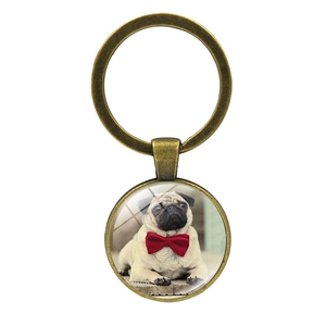 Close-up of bronze metal keychain featuring a cute pug dog with a red bow tie design