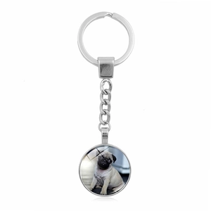 Macro view of a polished silver metal keychain featuring a cute Pug dog glass pendant