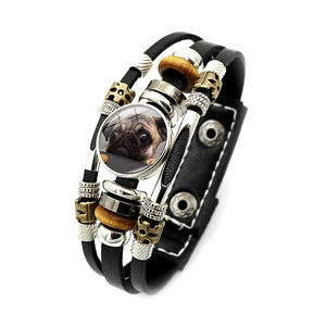 Close-up of a pug photo glass charm on a punk-style multilayer leather bead bracelet