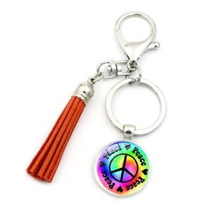 Detail of peace symbol glass pendant and vibrant orange suede tassel on silver keychain