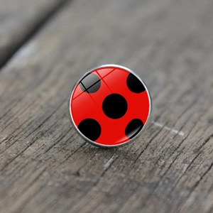 Macro view of ladybug polka dot glass dome ring with silver metal base on wood texture