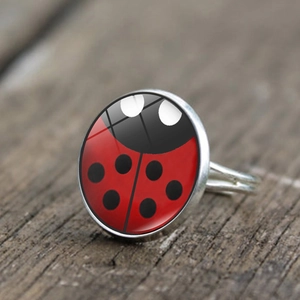 Macro shot of a silver adjustable ring featuring a red and black ladybug glass cabochon