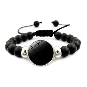 Detail of adjustable black matte beaded bracelet with custom round metal pendant