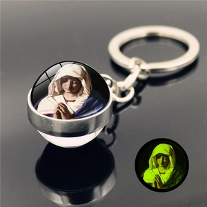 Macro view of crystal glass ball keychain with luminous glowing Virgin Mary religious icon