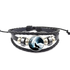 Detailansicht eines Wolf-Mond-Glascabochons auf schwarzem geflochtenem Lederarmband